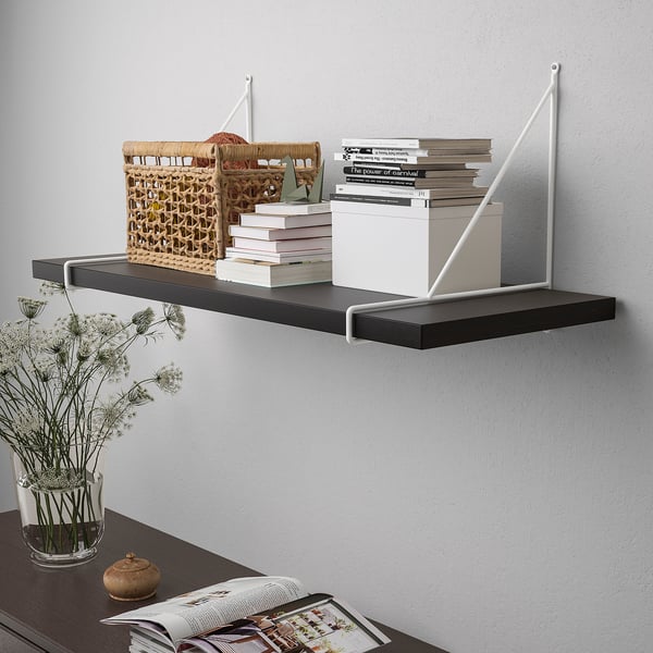 Wall-mounted shelf with books, storage basket, and decorative vase. Simple, versatile storage solution.