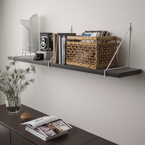 Wall-mounted shelf with various items: books, basket, camera, and vase with flowers. The shelf supports up to 20 kg when properly mounted.