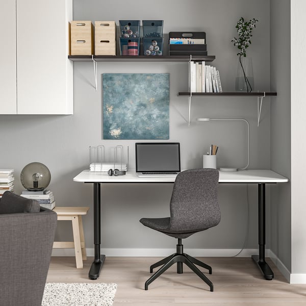 Modern home office with BERGSHULT shelves, desk, laptop, and plant.