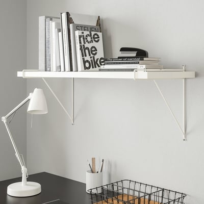 White BERGSHULT shelf with books and lamp.
