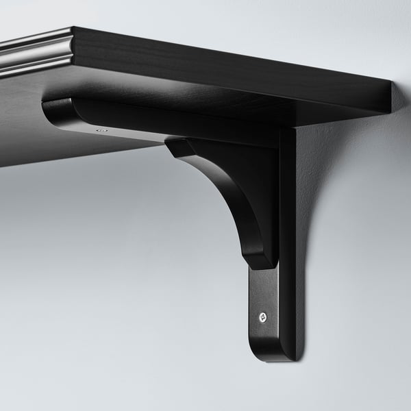 Black wall-mounted shelf with sleek, curved design and sturdy brackets, securely attached to a grey wall.