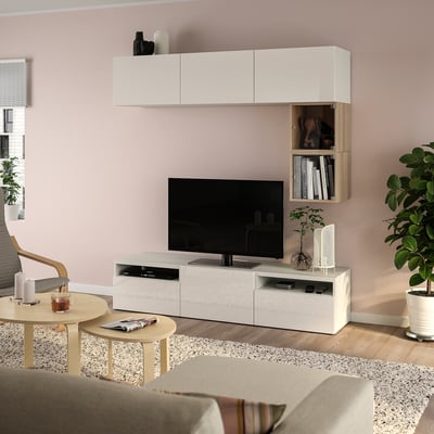 Modern living room with BESTÅ tv bench in white, pink walls, plants, and beige sofa.
