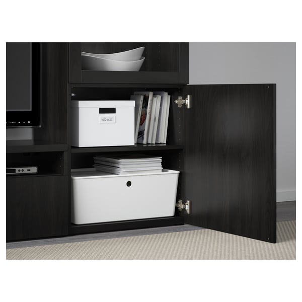 Black BESTÅ cabinet with open door, showing organised storage including stacked files, books, and a white storage box.