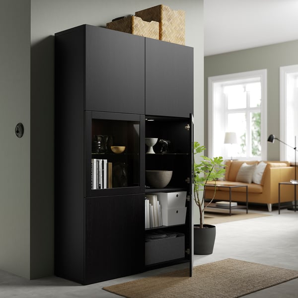 Black BESTÅ cabinet with glass doors decorative items while hiding clutter. Adjustable shelves and doors with soft-closing hinges.