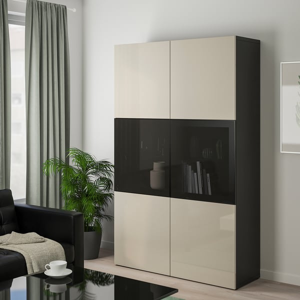 Modern BESTÅ storage cabinet with beige & black doors, tall with items behind glass.