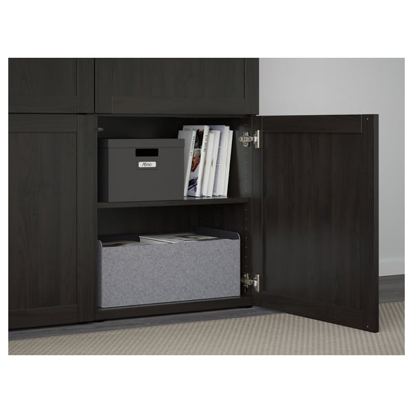 Open dark wood cabinet showing adjustable shelves with storage bins and books.
