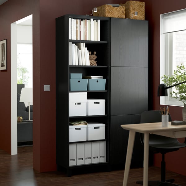 Black BESTÅ bookshelf, tall with open/closed storage, fits between door and desk.