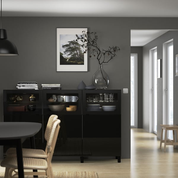 Modern black BESTÅ sideboard with glass doors against grey wall.