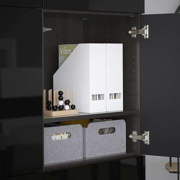 Black BESTÅ cabinet with adjustable shelves holding white boxes and gray bins, showcasing organized storage.