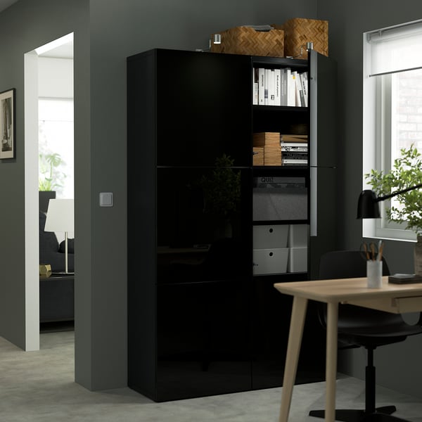 Black BESTÅ storage unit with adjustable shelves and soft-closing doors, storing files and decor.