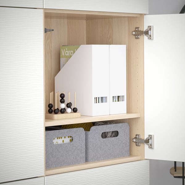 Open wooden cabinet with adjustable shelves, holding grey storage boxes, a magazine, and decorative items. Hinges allow door adjustments.