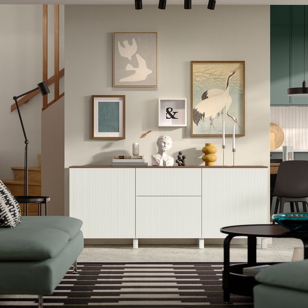 Minimalist living room with BESTÅ sideboard, art, turquoise sofa, black chair.