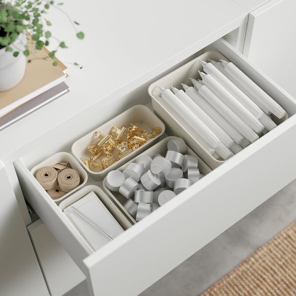 Open drawer with organised office supplies: tape, clips, ribbons, and pens neatly arranged in compartments.