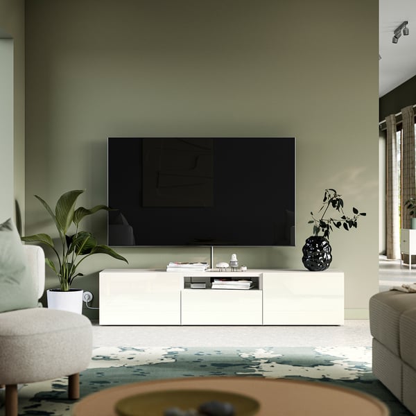 Flat-screen tv on BESTÅ bench with storage, green wall, plant, vase.