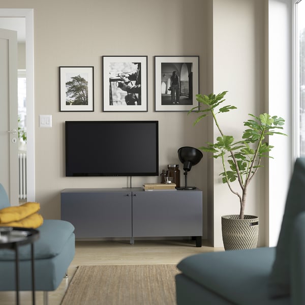 Modern living room with BESTÅ tv stand, flatscreen, black & white photos, blue seating & tall plant.