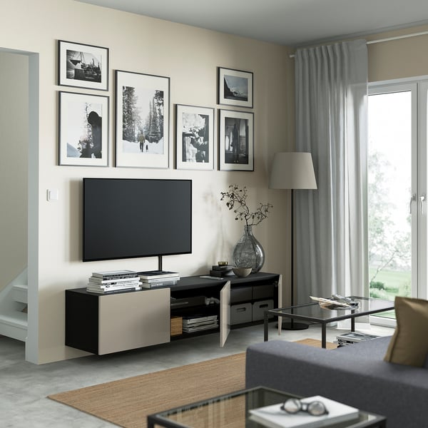 BESTÅ tv bench with adjustable shelves and cable management, holding a tv and decor against a wall with stylish black-and-white pictures.