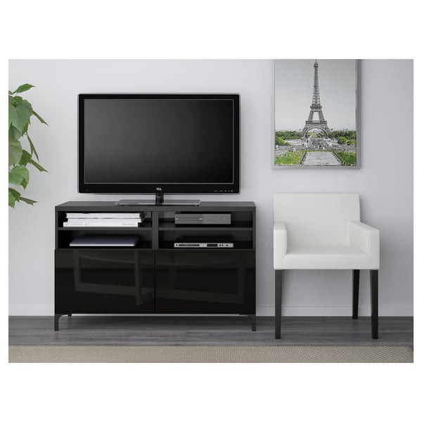 Modern living room setup: black tv stand with storage, flat-screen tv, white chair, and eiffel tower artwork.