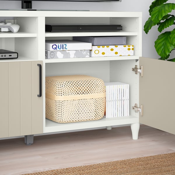 White BESTÅ tv bench with adjustable shelves, cable management, and soft-close hinges. Woven basket and storage boxes visible.