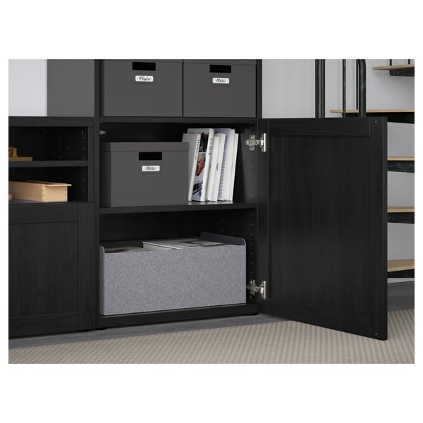 Black storage cabinet with adjustable shelves and cable management, holding grey boxes and books.
