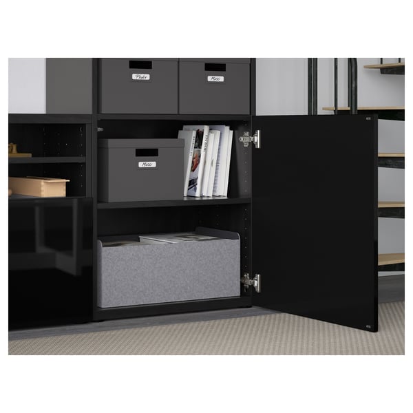 Black BESTÅ cabinet with shelves, grey bins, and books, showing cable management and adjustable shelves.