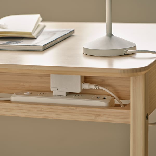 A wooden desk with a built-in power outlet and cord manager, keeping the workspace tidy and organised.