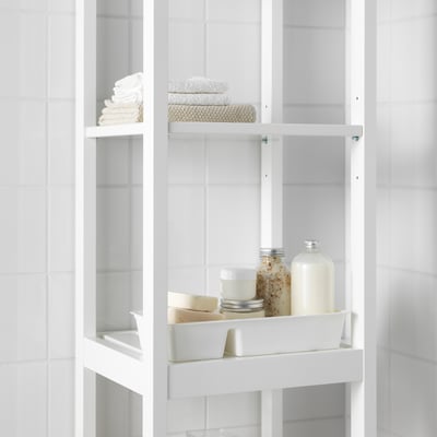 White shelf unit with stacked towels and bathroom products, including bottles and containers, demonstrating organised storage.