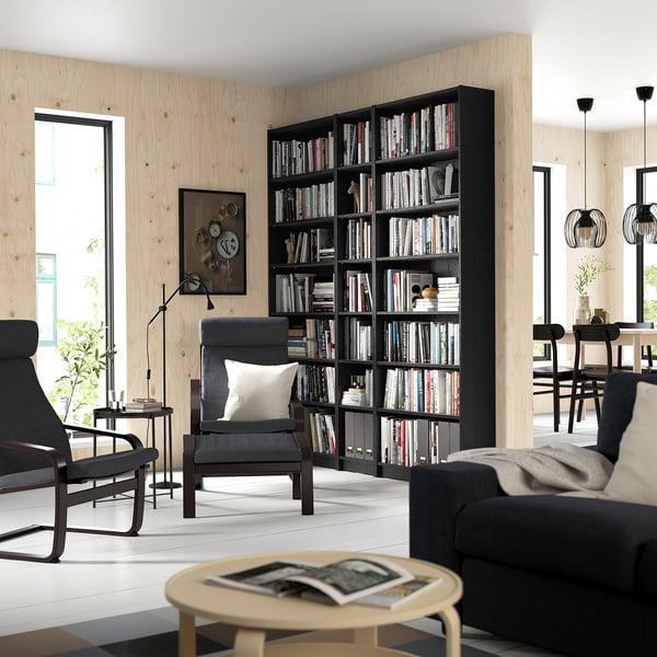 Room with large BILLY bookcase, armchair, coffee table, dining area, and pendant lamps.