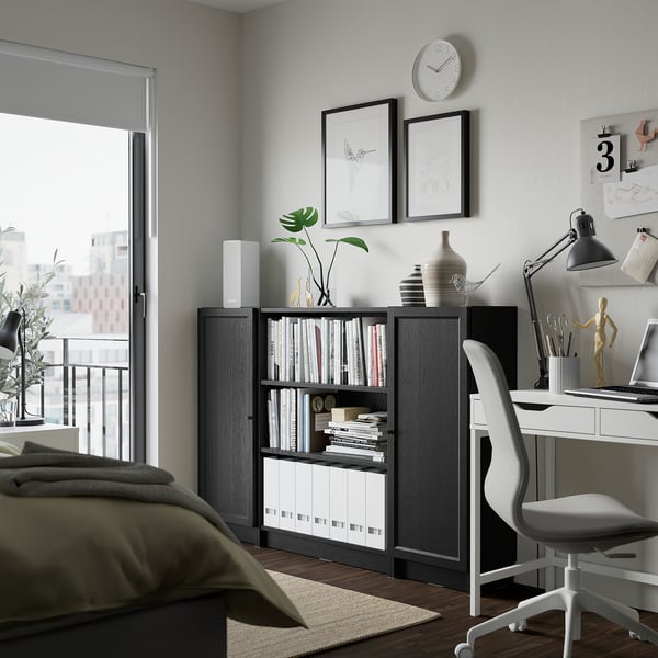 Modern living space with dark wood BILLY bookcase, desk, bed, and decor.