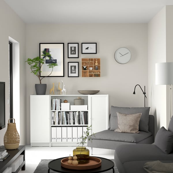 Modern living room with white BILLY bookcase, grey sofa, coffee table, plant, and wall clock.