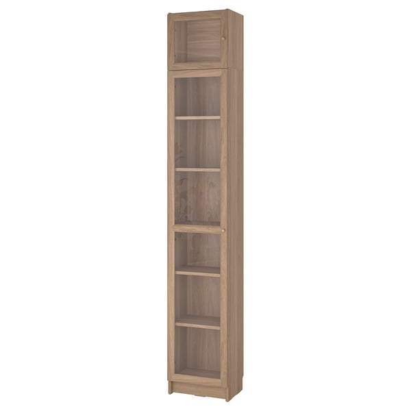 Tall wooden BILLY bookcase with glass doors, light brown finish, five shelves, sleek design.