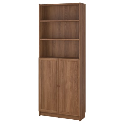 A BILLY bookcase in brown. It both open and closed storage with adjustable shelves and tasseled doors. The wooden texture gives a warm, natural feel.