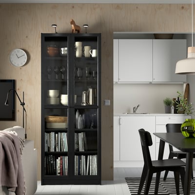 Modern room with BILLY bookcase, dishes, glasses, books, clock.