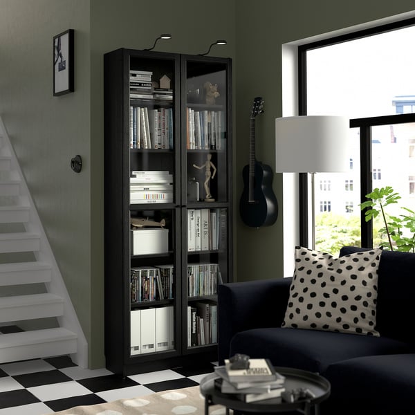 Modern living room with dark BILLY bookcase, sofa, guitar, side table, and lamp. Green wall, chequered floor, and window view.