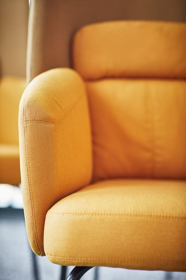Bright yellow BINGSTA armchair with rounded edges, slim legs, offering cosy comfort.