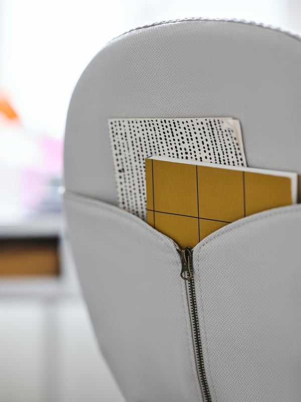 Grey BJÖRKBERGET chair with yellow notepad in pocket. Modern, sleek design.