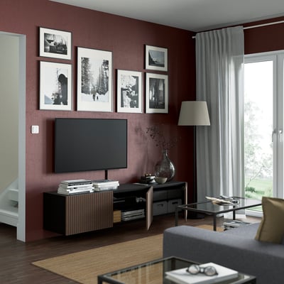 Modern living room with dark oak veneer cabinet, flat-screen tv, framed photos, lamp, and glass coffee table by window.