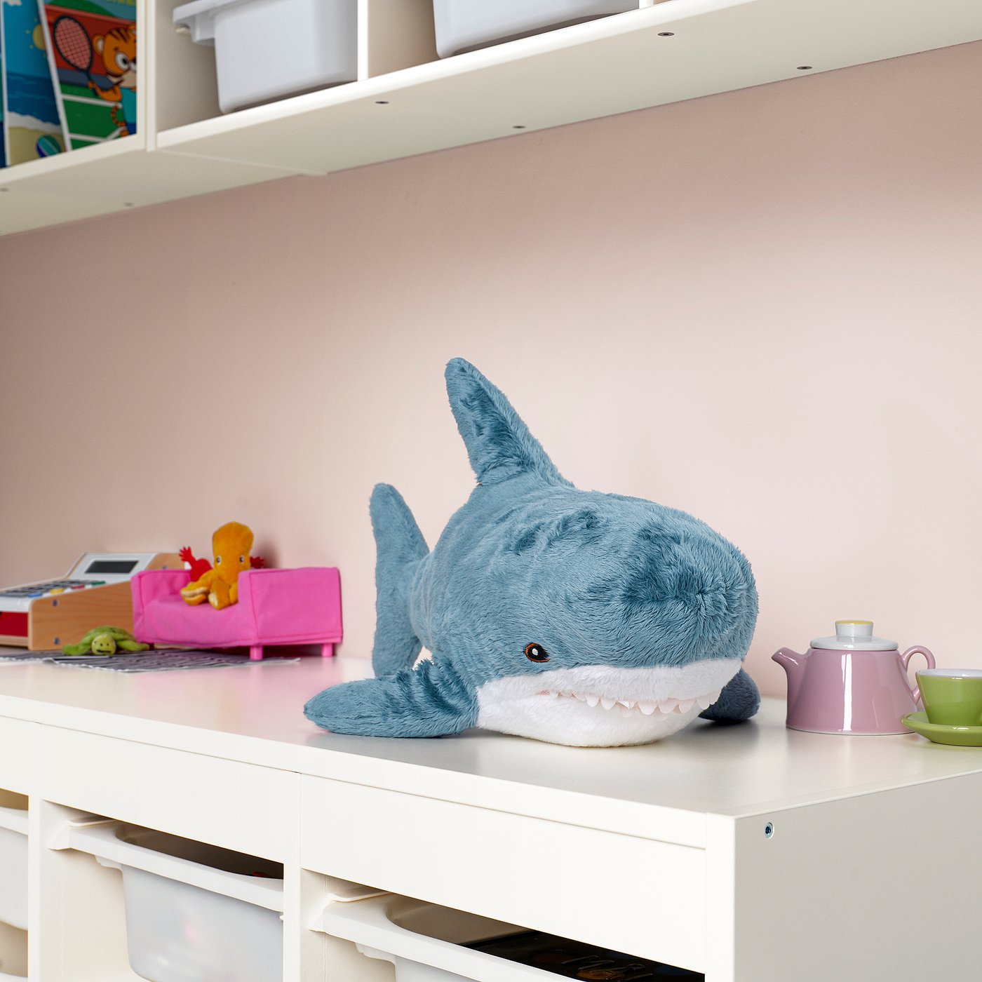 Blue shark plush on shelf with dollhouse items.