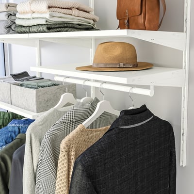 Well-organized closet with white shelves and hanging rod. Clothes, grab, and hat neatly arranged; sturdy, space-saving design.