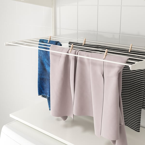 Clothes drying on a wall-mounted rack, organised with wooden pegs.