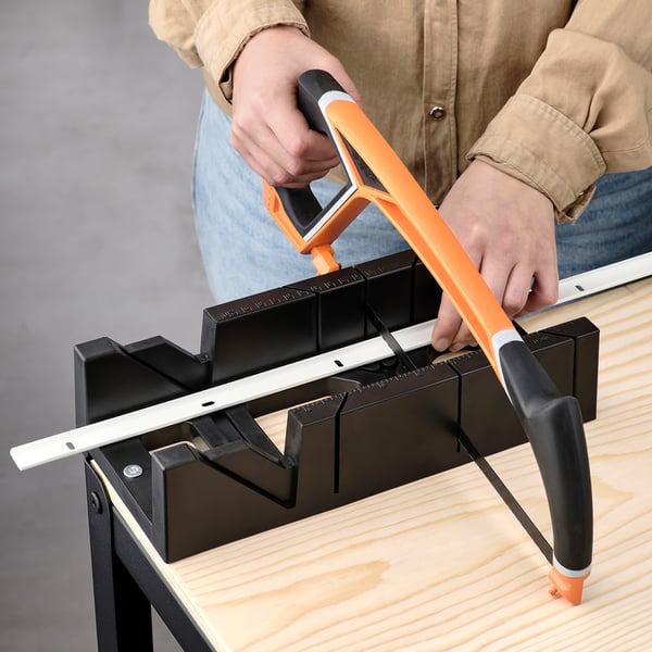 A person uses a tool to align a mounting rail for wall uprights, ensuring a straight setup.