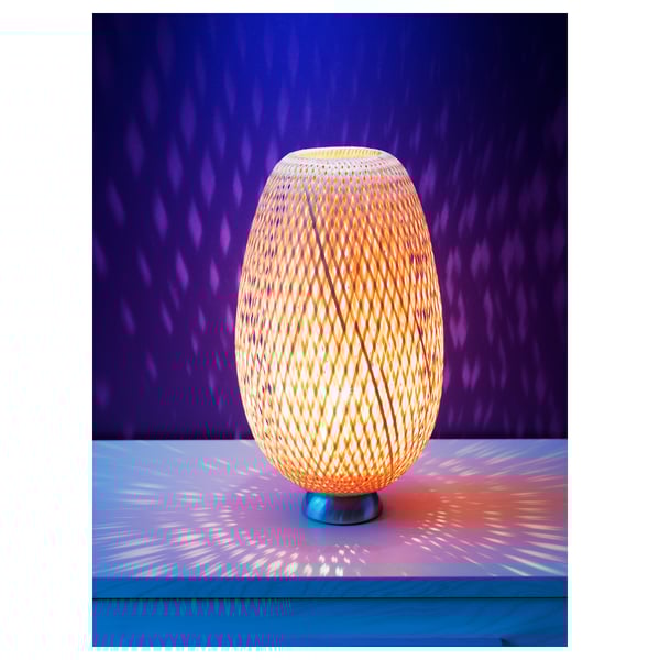 Bamboo table lamp with orange light, oval shape, casting intricate patterns.