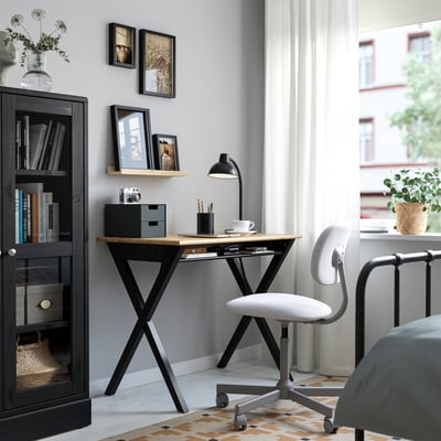The BOLLPOJKE desk with a light wooden top, black metal legs, and a simple, functional design.