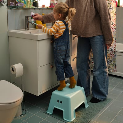 Child on BOLMEN stool brushing teeth with adult.
