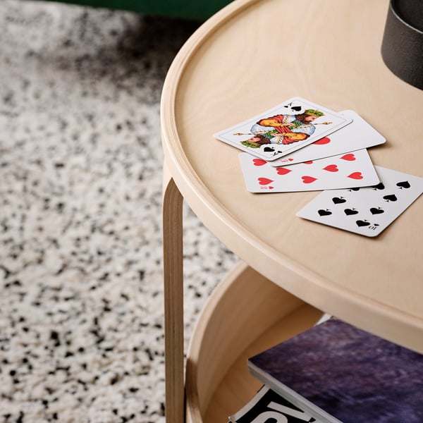 Playing cards on sleek, light wood side table with curved edges.