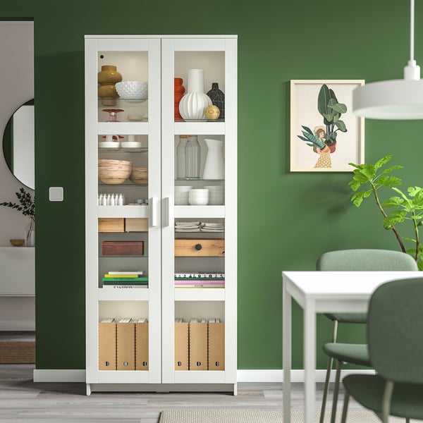 BRIMNES: white cabinet with glass doors, personal items, green wall.