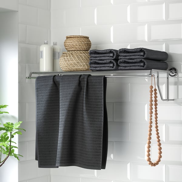 Metal shelf with towel rack, holding towels and baskets, featuring chrome details.