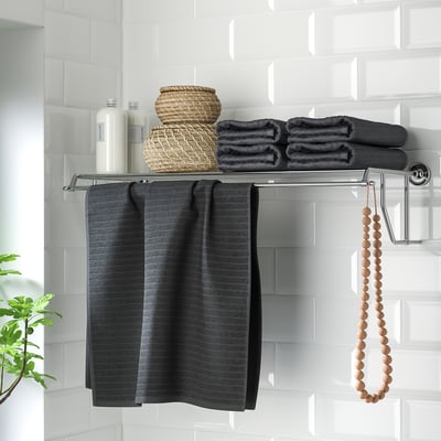 Metal shelf with towel rack, holding towels and baskets, featuring chrome details.