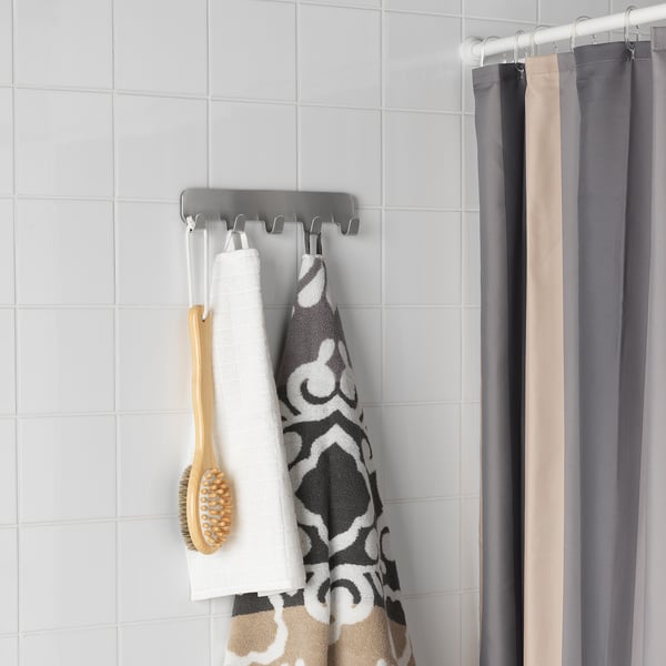Grey rack with white & patterned towels, brush, near shower curtain