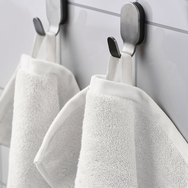 Two white towels hang on modern black hooks in a bathroom.