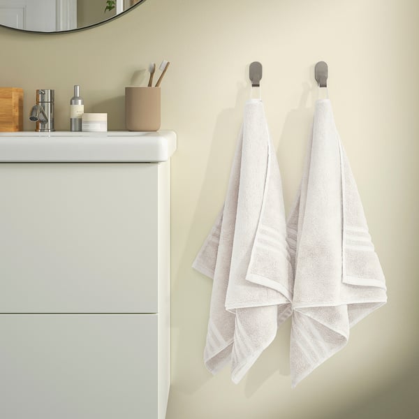 Two organic towels hang on hooks by sink. Thick, soft cotton with woven border. Toiletries on counter.